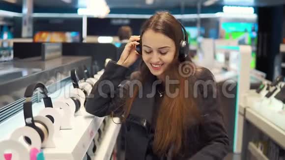 美丽的女人在现代商店测试耳机视频的预览图