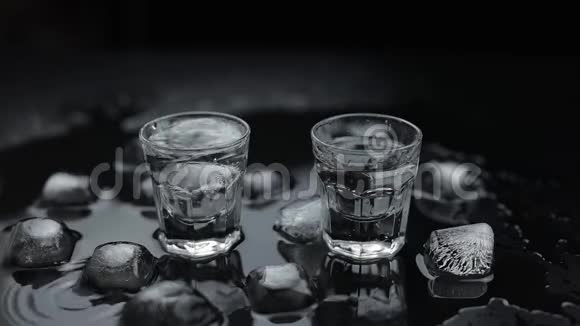 在杯中加入冰块在黑色背景下加入伏特加酒精饮料视频的预览图