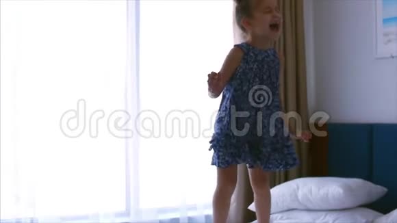 快乐的白种人女孩在床上跳慢动作视频的预览图