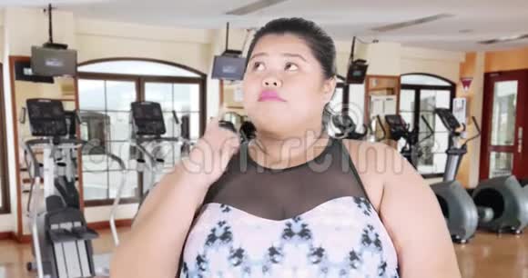 快乐超重的女人在健身房思考视频的预览图