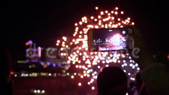 人手握智能手机拍摄一段晚上烟花的视频人物和建筑在背景下慢动作视频的预览图