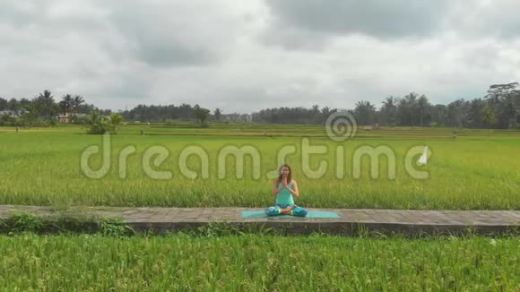 一位年轻女子用巴厘岛的方式为穆拉哈拉查克拉做冥想的慢镜头视频的预览图