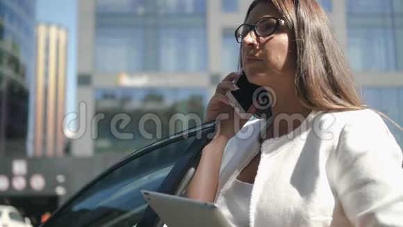 年轻的公共汽车律师正在打电话拿着平板电脑站在城市街道上视频的预览图