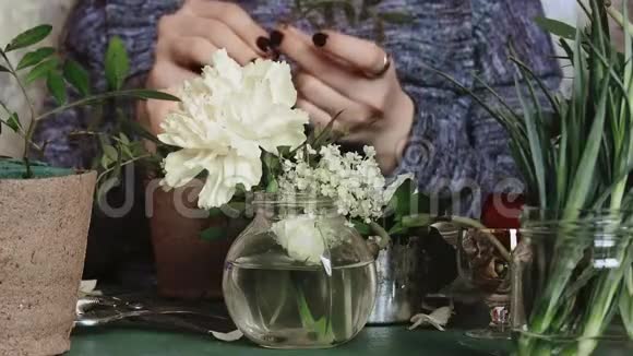 女孩剪了花的茎前景是一个花瓶和一朵白色的花视频的预览图