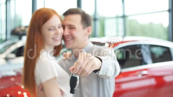 漂亮的一对夫妇拿着他们新车的钥匙看着相机微笑着视频的预览图