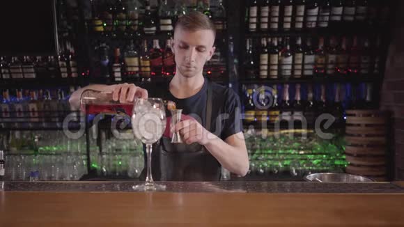 酒吧老板把酒从玻璃瓶中倒入高杯加冰的鸡尾酒杯年轻人在做美味的鸡尾酒视频的预览图