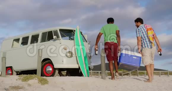 在海滩上携带冷藏箱的男性朋友视频的预览图