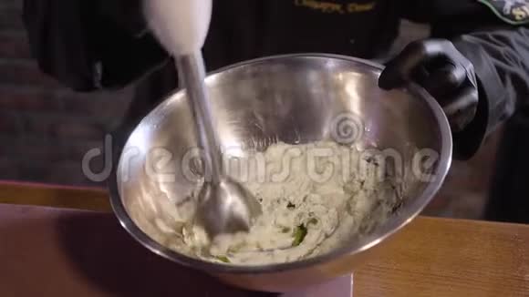 用大铝碗中的搅拌机将厨师用黑色橡胶厨师手套用欧芹搅拌奶油视频的预览图