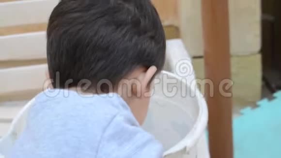 两岁的男孩在玩白色桶里的泥土视频的预览图
