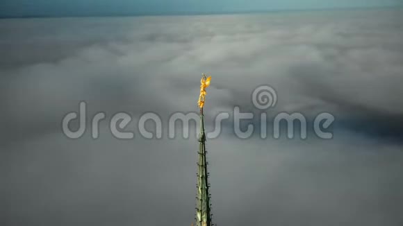 在圣米歇尔山顶上的金色圣米迦勒雕像周围飞行塔尖在云层上方的阳光下发光视频的预览图
