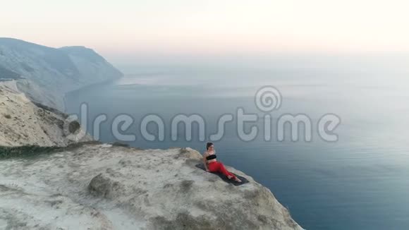 美丽的女人正在做瑜珈南体在山上侧卧抬腿日落时可以看到海景视频的预览图
