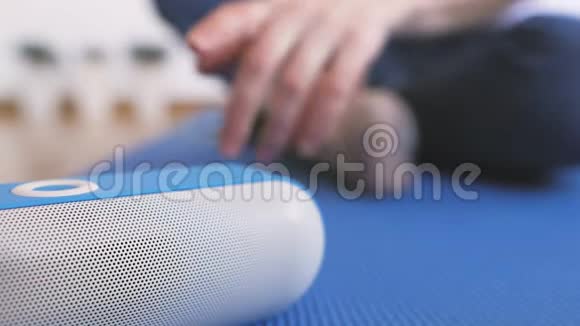 一个坐在地板上的女人打开一个便携式蓝牙扬声器愉快地听音乐视频的预览图