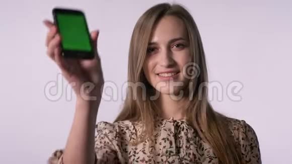 年轻开朗的女人展示了绿色的智能手机屏幕微笑相机手表交流理念白色视频的预览图