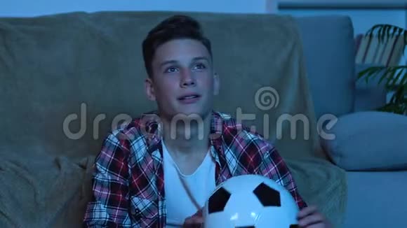 年轻人为最喜欢的足球队获胜而高兴在家看比赛视频的预览图