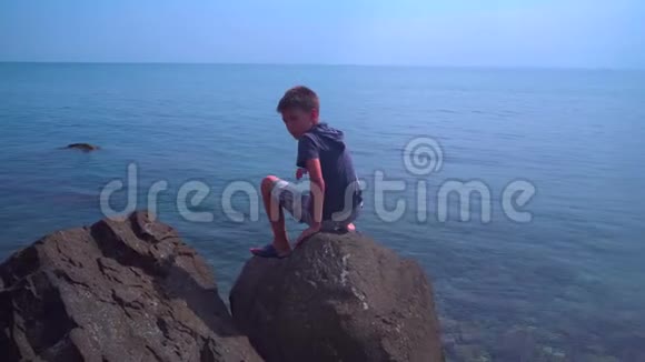 男孩在海滨攀爬天然石头和岩石找螃蟹视频的预览图