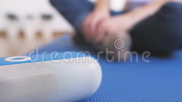 一个坐在地板上的女人打开一个便携式蓝牙扬声器愉快地听音乐视频的预览图