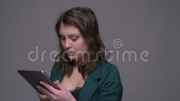 拍摄一张成年漂亮的深色头发女性的特写镜头她在平板电脑上发短信看着背景隔离的相机视频的预览图