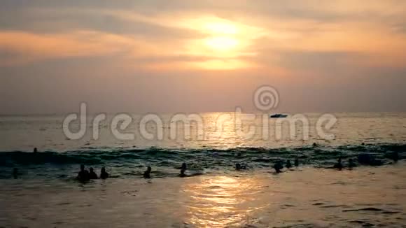 日落时分许多人在海边的巨浪上摇摆视频的预览图