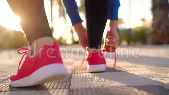 在日落时分女人系鞋带沿着棕榈大道奔跑背面视频的预览图