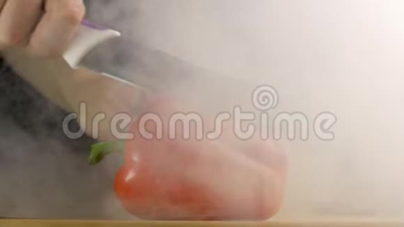 一个人用刀把一根新鲜的保加利亚胡椒切在烟里特写慢一点视频的预览图