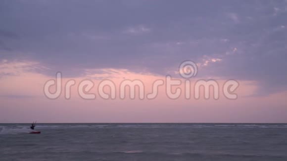 慢镜头拍摄一个穿红色风筝的人在多云的早晨漂浮在海面上视频的预览图