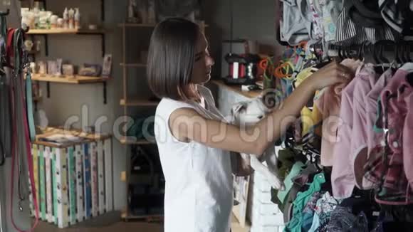 漂亮的女人为她的狗挑选衣服视频的预览图