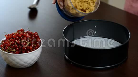 一个女人正在打碎饼干用红醋栗做精致的芝士蛋糕视频的预览图