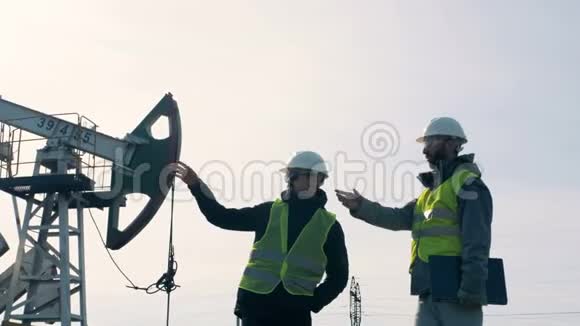两名工人在采油设备附近交谈过程视频的预览图