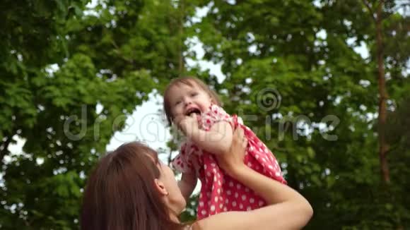 小女孩在妈妈的手里跳着笑着妈妈在夏天公园和她女儿玩慢慢视频的预览图