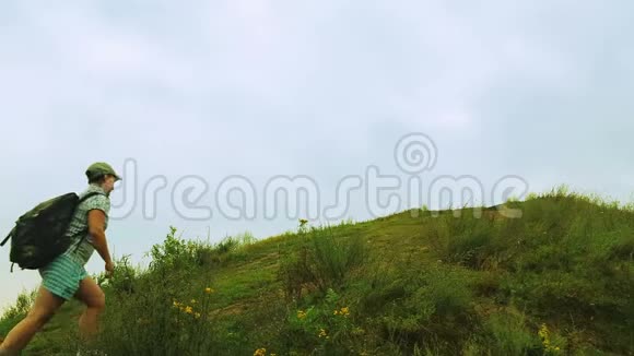 一位背着背包的女游客爬上了一座覆盖着绿色植被的山视频的预览图