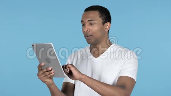 非洲男子通过平板电脑进行视频聊天蓝色背景视频的预览图