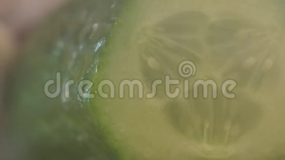 一个人在黑黑的背景下把黄瓜切成薄片在烟雾中宏观的缓慢的自然的视频的预览图