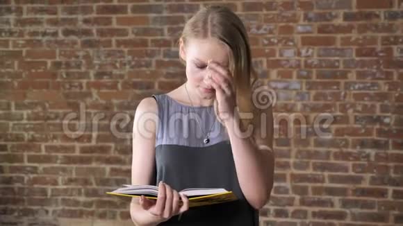 年轻的涉案金发女孩正在看书砖背景视频的预览图