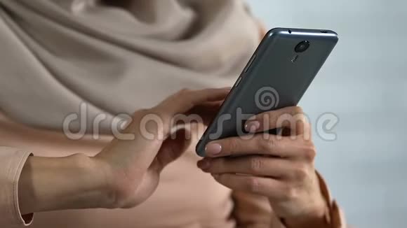 穆斯林妇女手在智能手机上滚动新闻在线观看视频应用程序视频的预览图