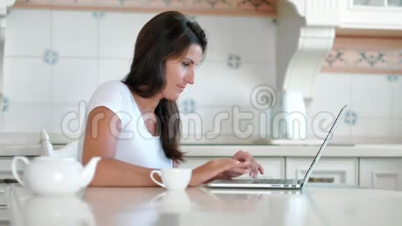 侧视微笑的年轻女子热情地用笔记本电脑在键盘上打字视频的预览图