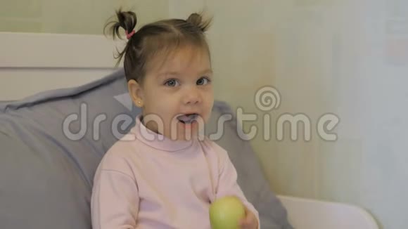 可爱的小女孩在床上吃苹果摆姿势拍照视频的预览图