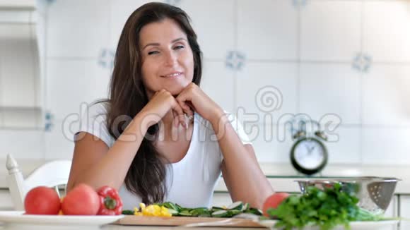 微笑的女性家庭主妇坐在餐桌前在家厨房休息的画像视频的预览图