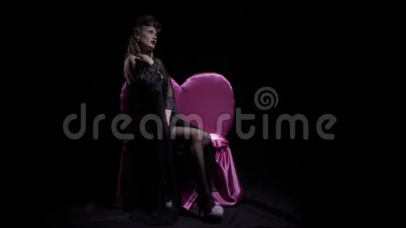 粉色沙发上的性感模特在深色背景上摆姿势4k视频的预览图