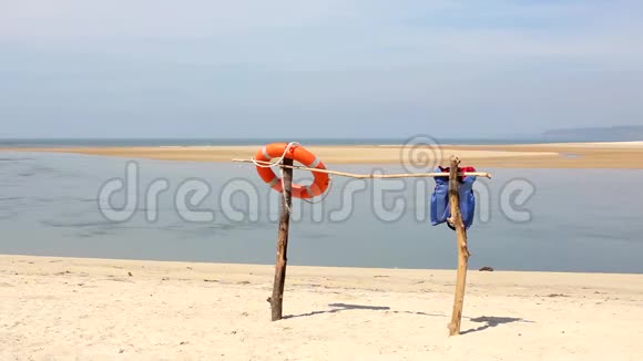沙滩上沙滩上的橙色救生圈和蓝色救生衣视频的预览图