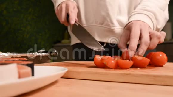 女孩的特写她的手在家里的厨房里用木切板刀小樱桃番茄用刀家庭视频的预览图