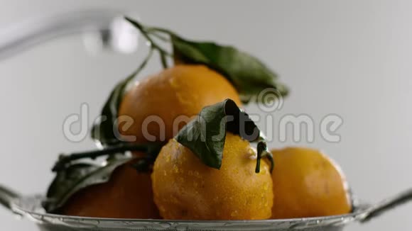 在视频中我们看到橘子橘子躺在滑梯上橘子上覆盖着水滴白色的背景视频的预览图