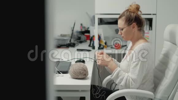 办公室里的成熟女人在编织一个女人在办公室打毛衣休息时坐在办公室里视频的预览图