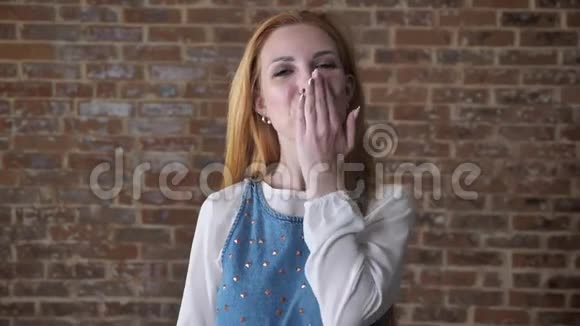 年轻迷人的金发女孩正在镜头前观看送一个吻调情的概念砖背景视频的预览图
