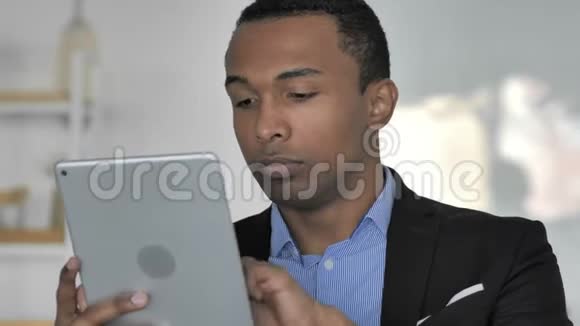近距离观看美国黑人商人在平板电脑上浏览互联网视频的预览图