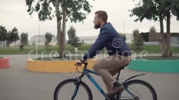 夏天英俊的长胡子男人在城市公园骑自行车视频的预览图