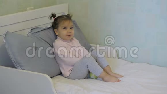 可爱的小女孩在床上吃苹果摆姿势拍照视频的预览图