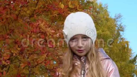 严肃的女孩在秋橙叶背景秋天公园的微笑女孩视频的预览图