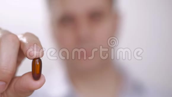 一个人用手指拿着药片时拿出一块药片然后把它吞下去用水喝视频的预览图