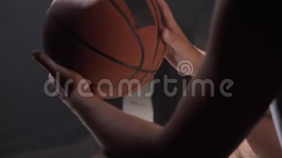 篮球运动员坐着玩球等着去黑暗迷蒙的房间里玩视频的预览图