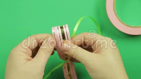 女人双手系着一条绿色丝带粉红色丝带空白作为绿色背景上的礼物蝴蝶结视频的预览图
